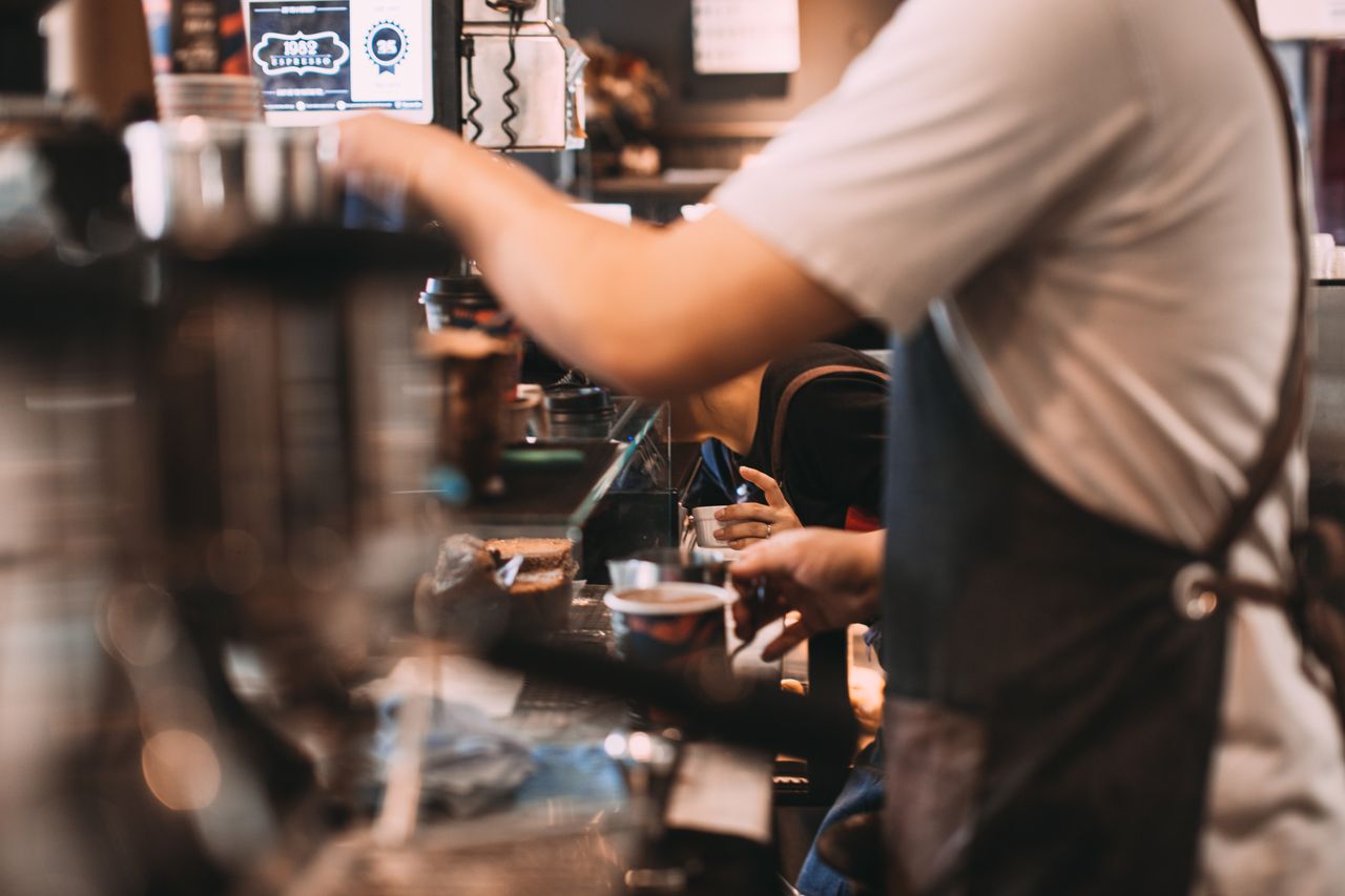 Medewerker die een taak afhandelt achter de bar